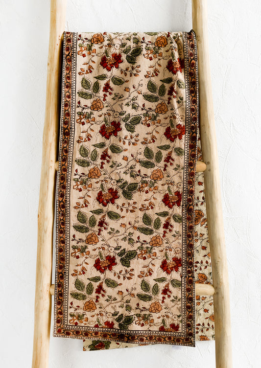A block printed table runner in crimson, green and beige floral print.