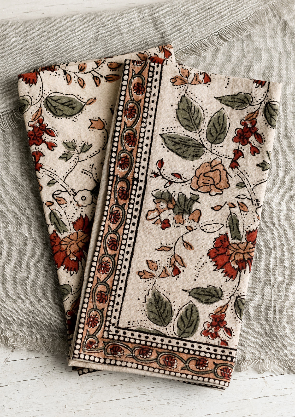 A pair of block printed napkins with burgundy floral print.