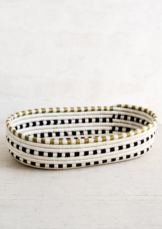 An oval shaped basket made from woven sweetgrass in black and white dash pattern.