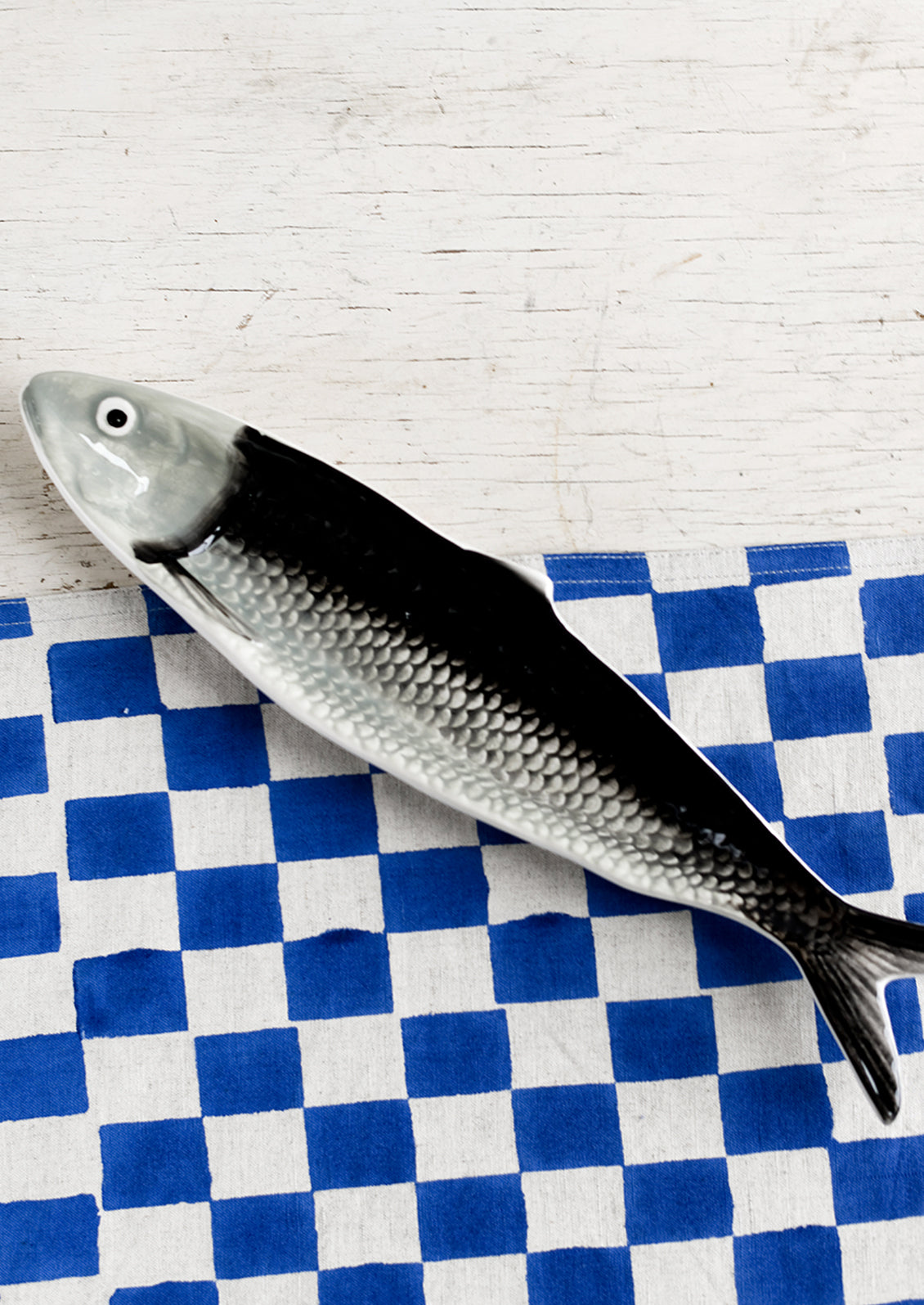 A ceramic tray in the shape of a sardine in black and grey.