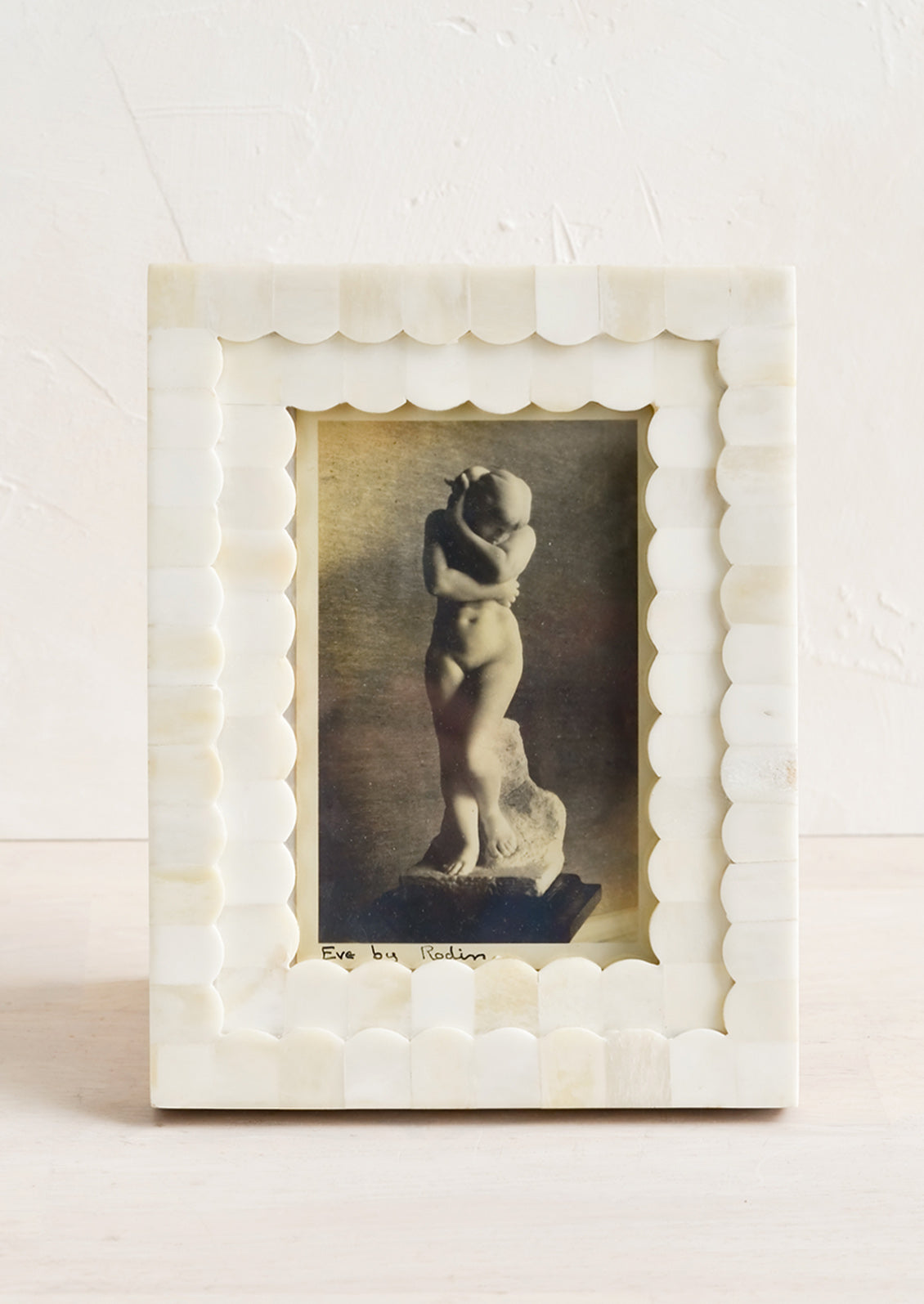 A tabletop picture frame with scalloped ivory bone border.
