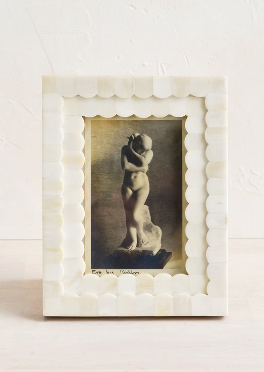 A tabletop picture frame with scalloped ivory bone border.