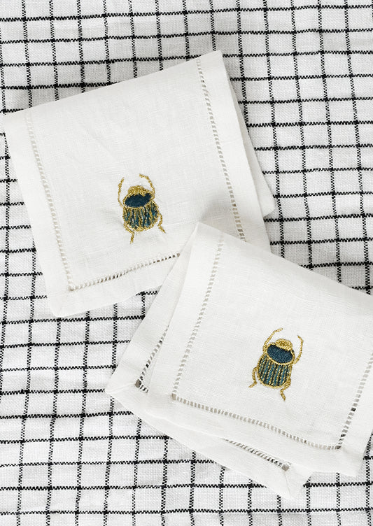 A pair of scarab embroidered cocktail napkins.