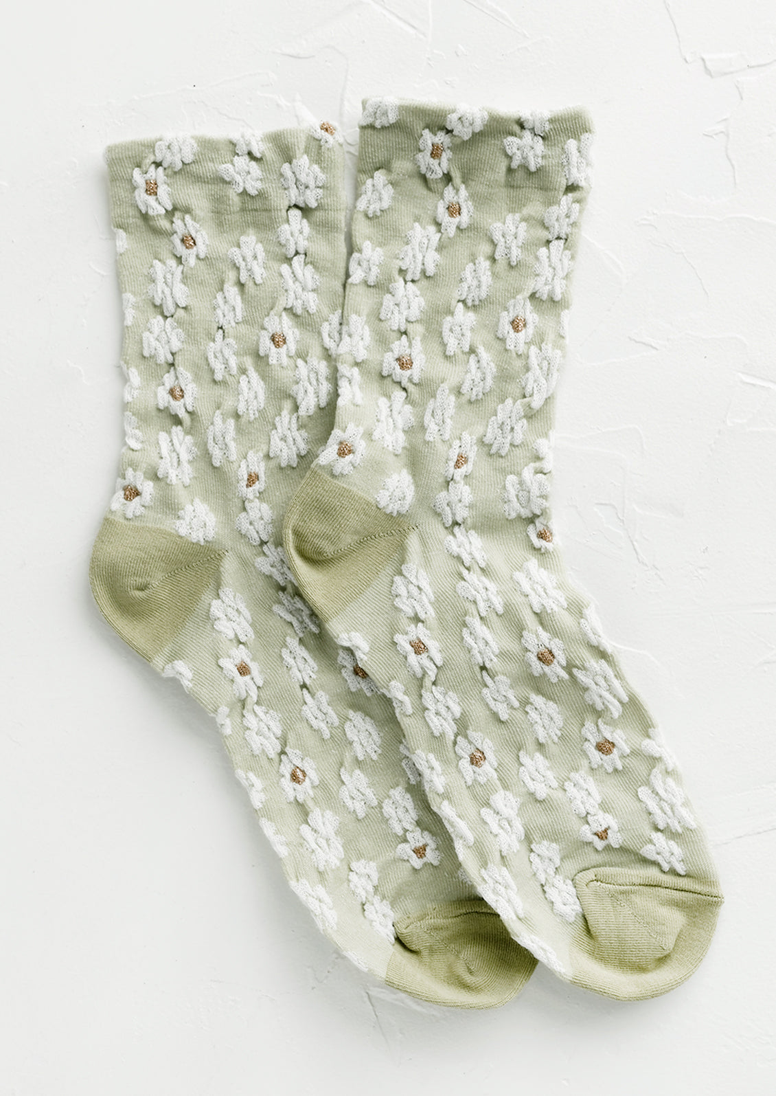 A pair of non-sheer yellow socks in mint with allover white daisy pattern.