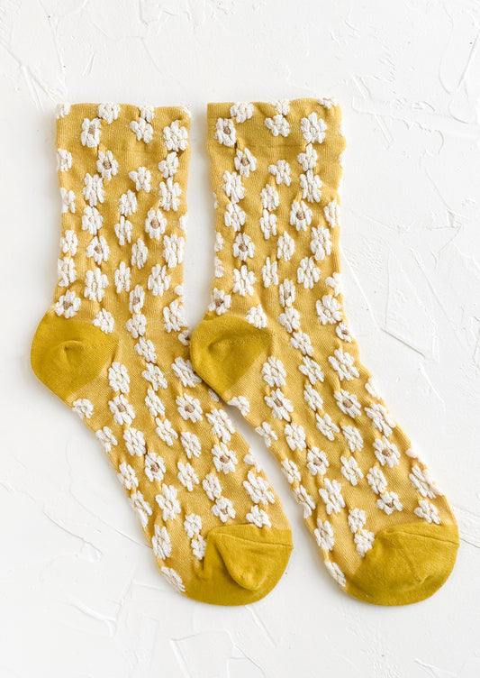 A pair of non-sheer yellow socks with allover white daisy pattern.