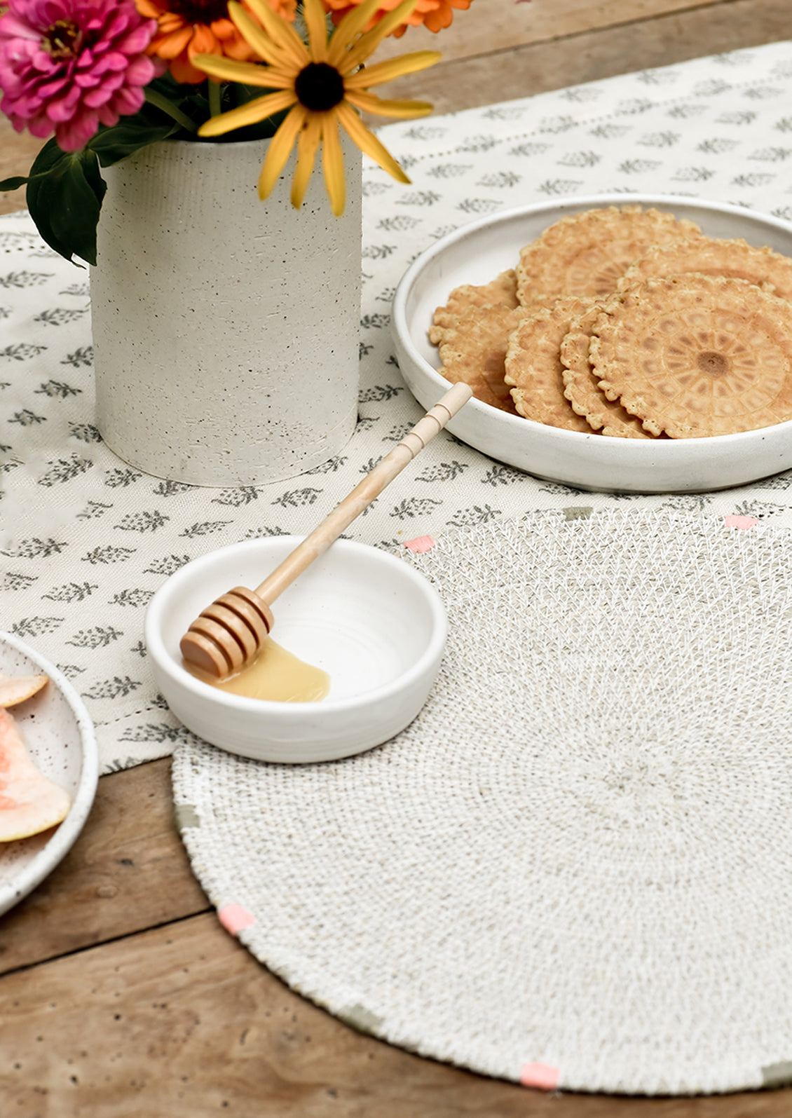 A table setting with placemat, vase and plates.