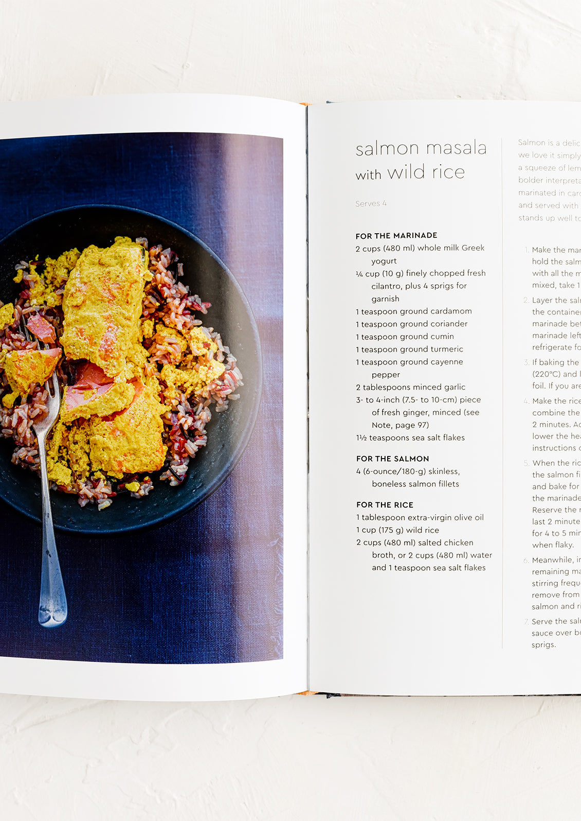 A cookbook open to a page with recipe for salmon masala with wild rice.