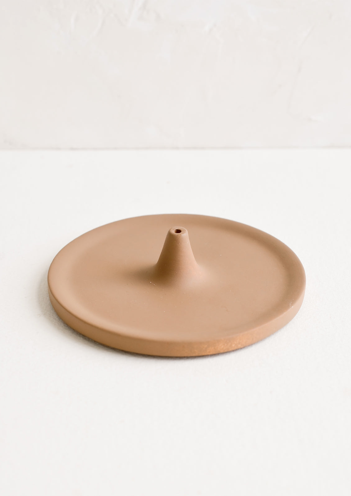 A round incense holder in matte brown ceramic.