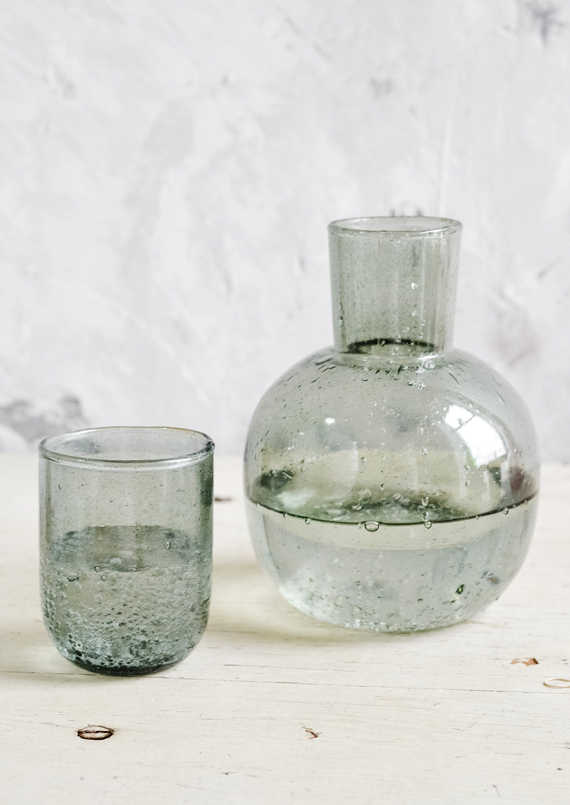 A glass carafe with lid/cup in grey.