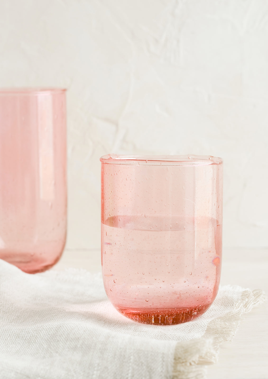 Short and tall glass tumblers in seeded pink glass.