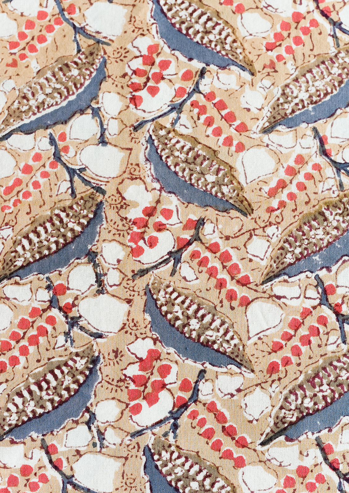 A block print tablecloth with tan, red and slate blue floral print.