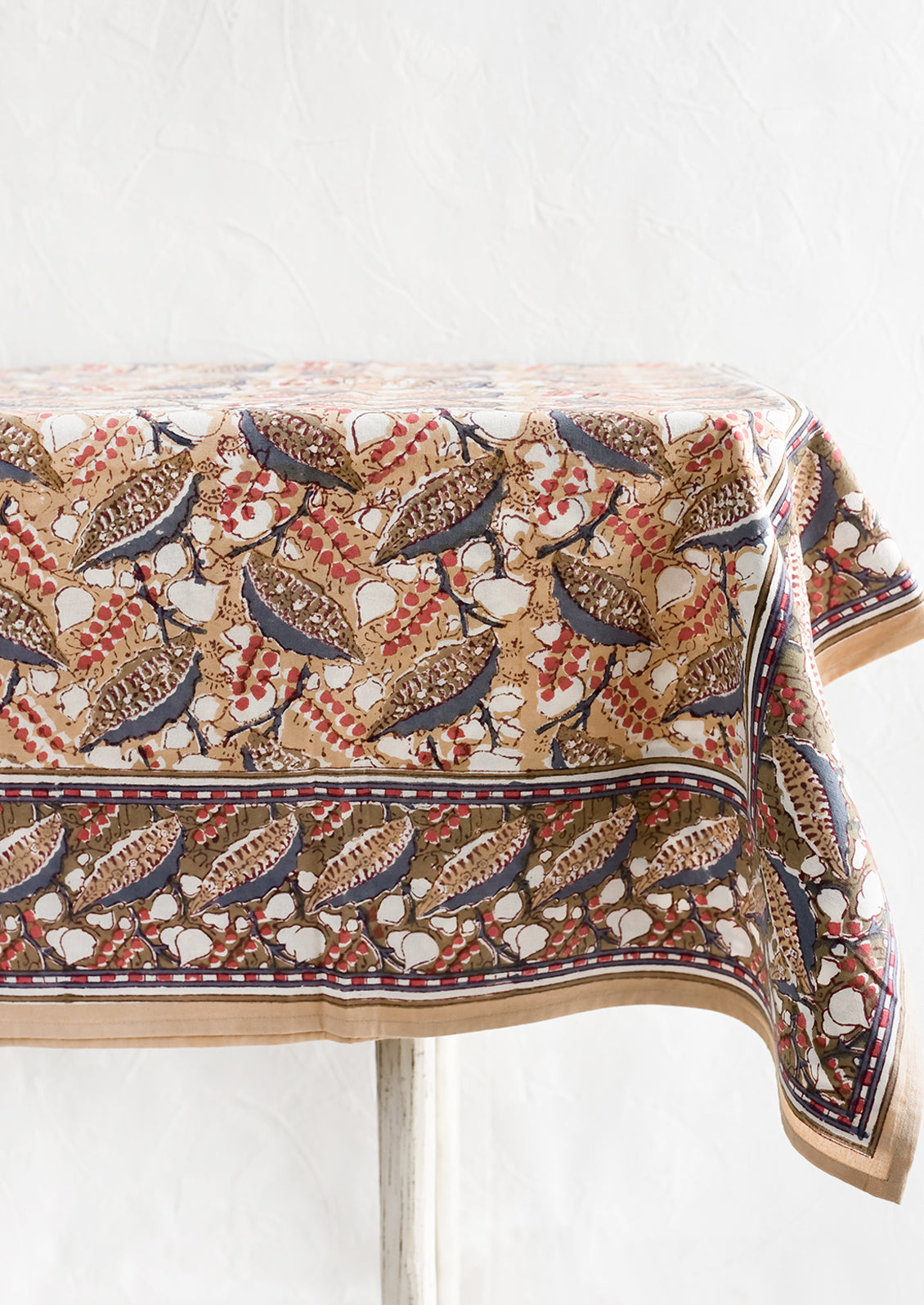 A block print tablecloth with tan, red and slate blue floral print.