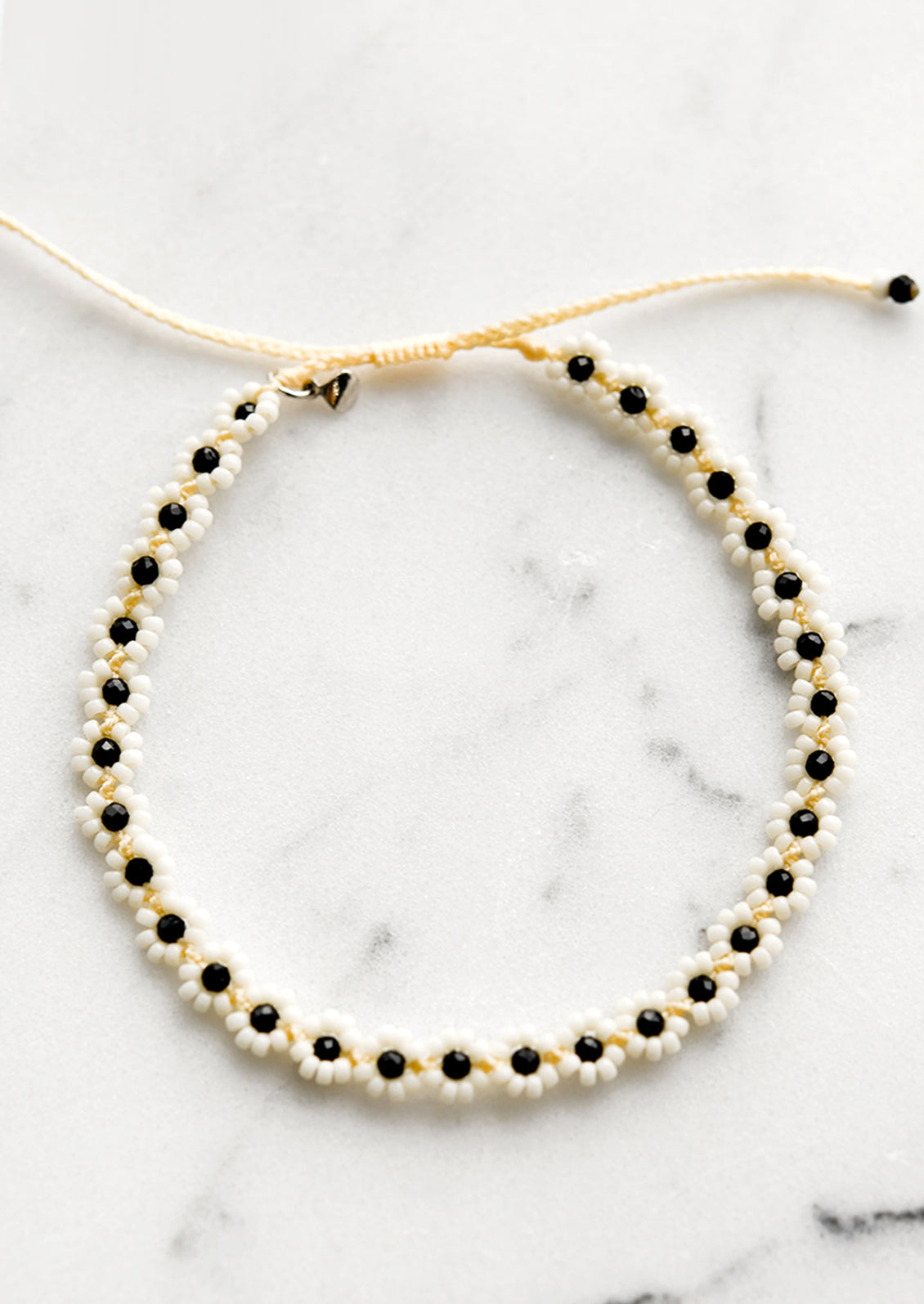 A beaded flower bracelet with cream and black beads.