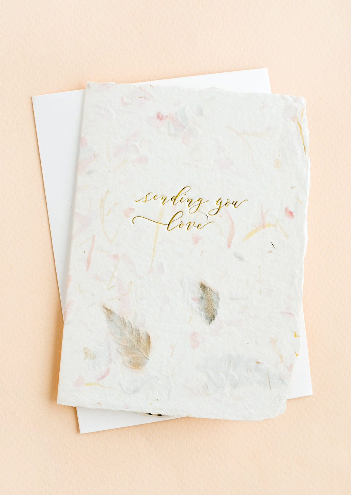 A greeting card made from handmade flower paper with gold script on front that reads "Sending You Love".