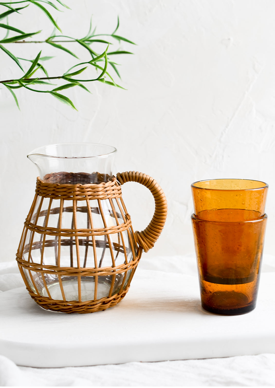 A seagrass wrapped pitcher and amber glass cups.