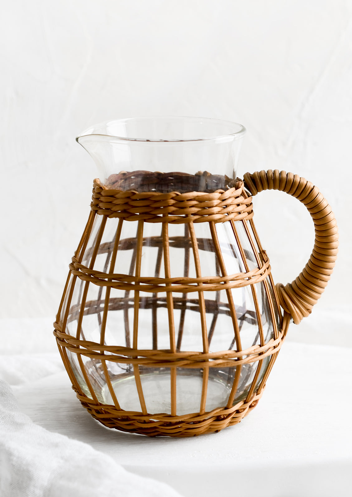 A round glass pitcher with sepia hued cage.