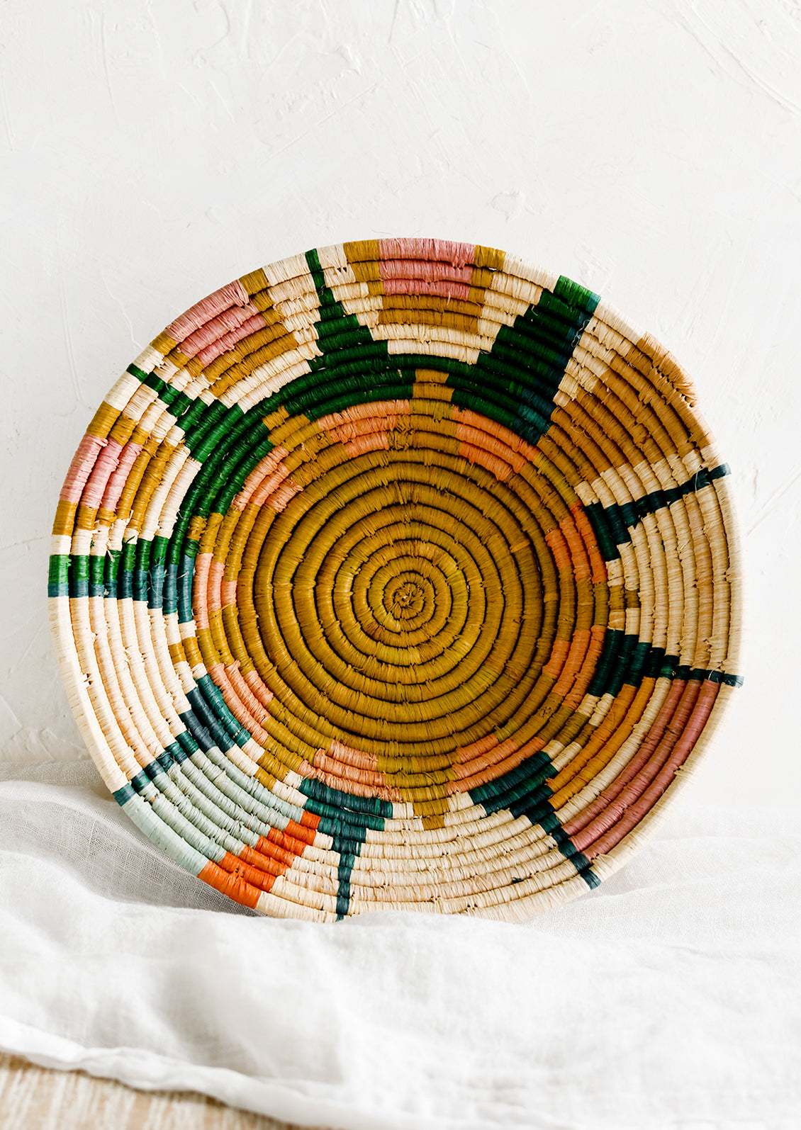 A woven raffia bowl with sunburst pattern.