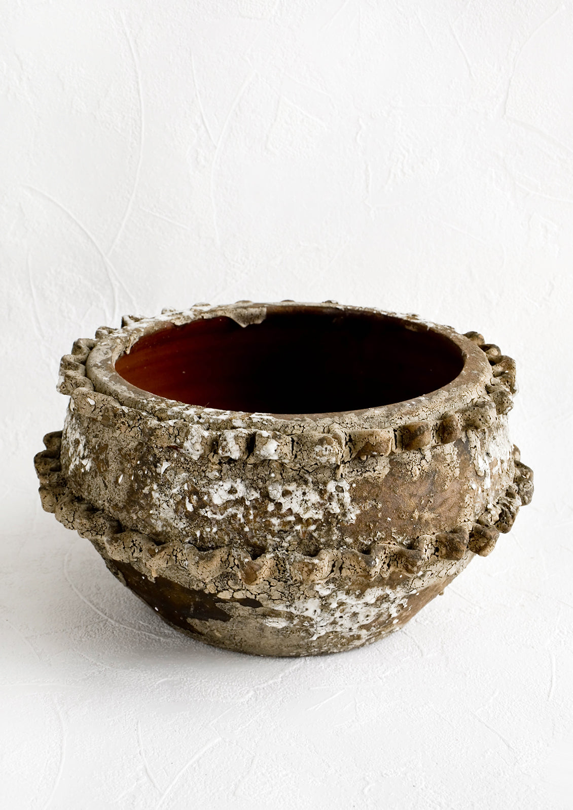 Distressed ceramic planter in chippy brown and white glaze with textured applique