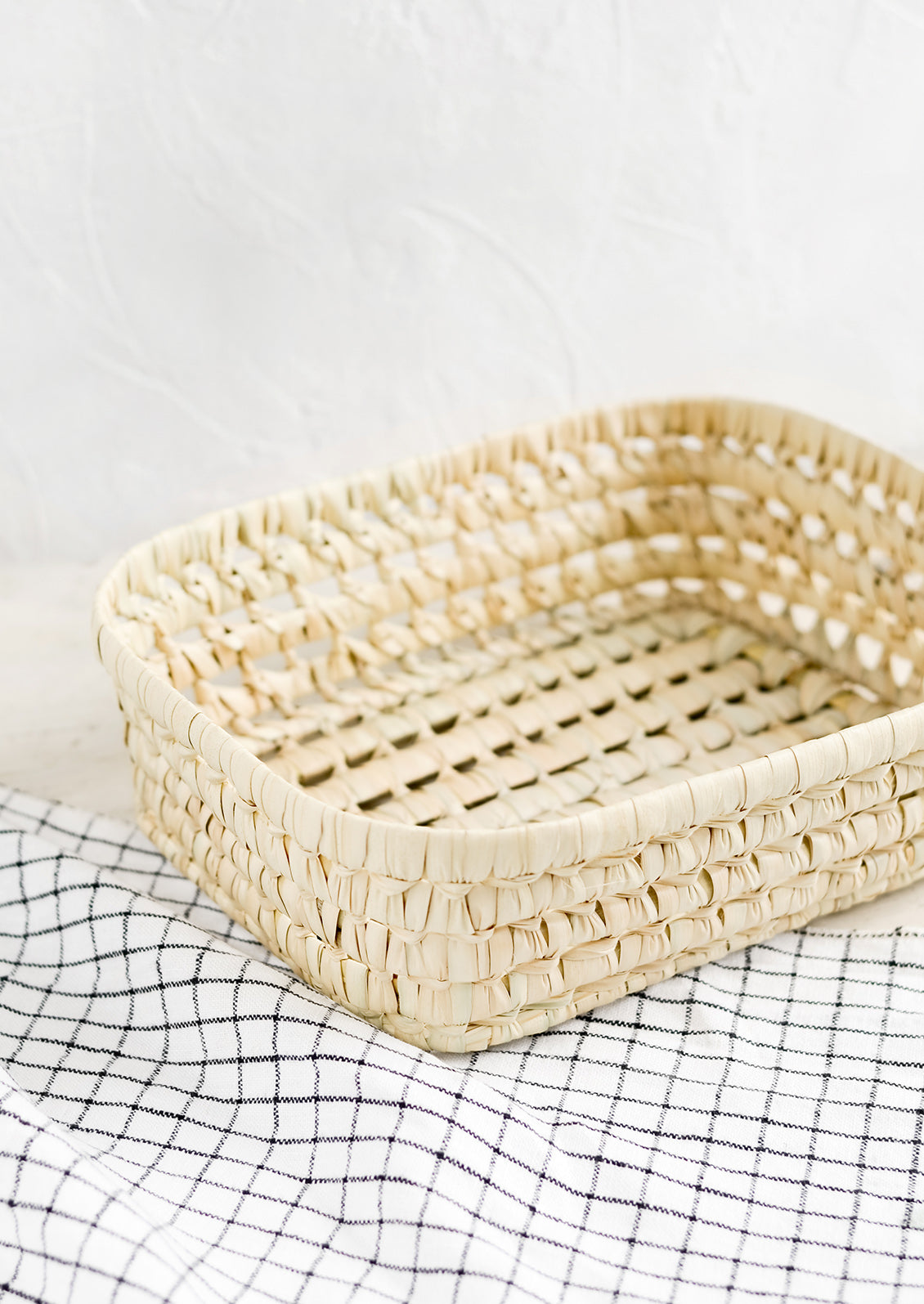 A shallow storage basket made from dried palm leaf.