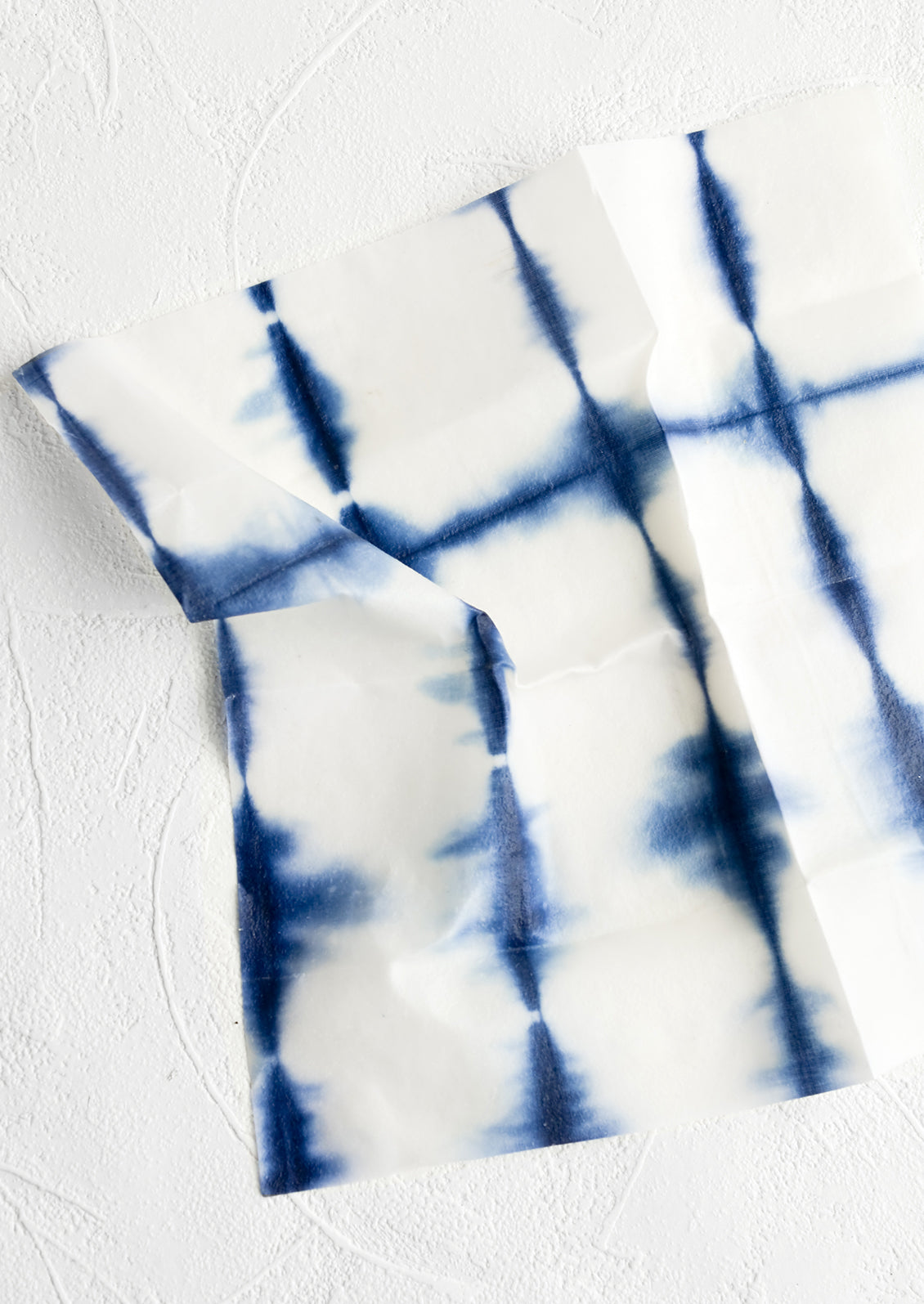 A beeswax wrap square in tie dye shibori print.