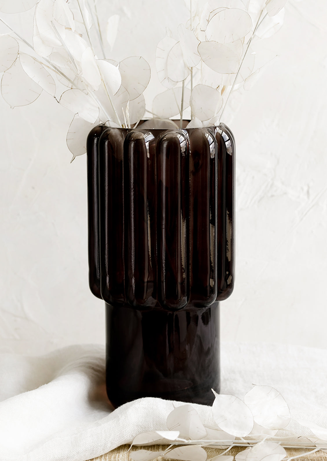 A large glass vase in dark brown with fluted texture.