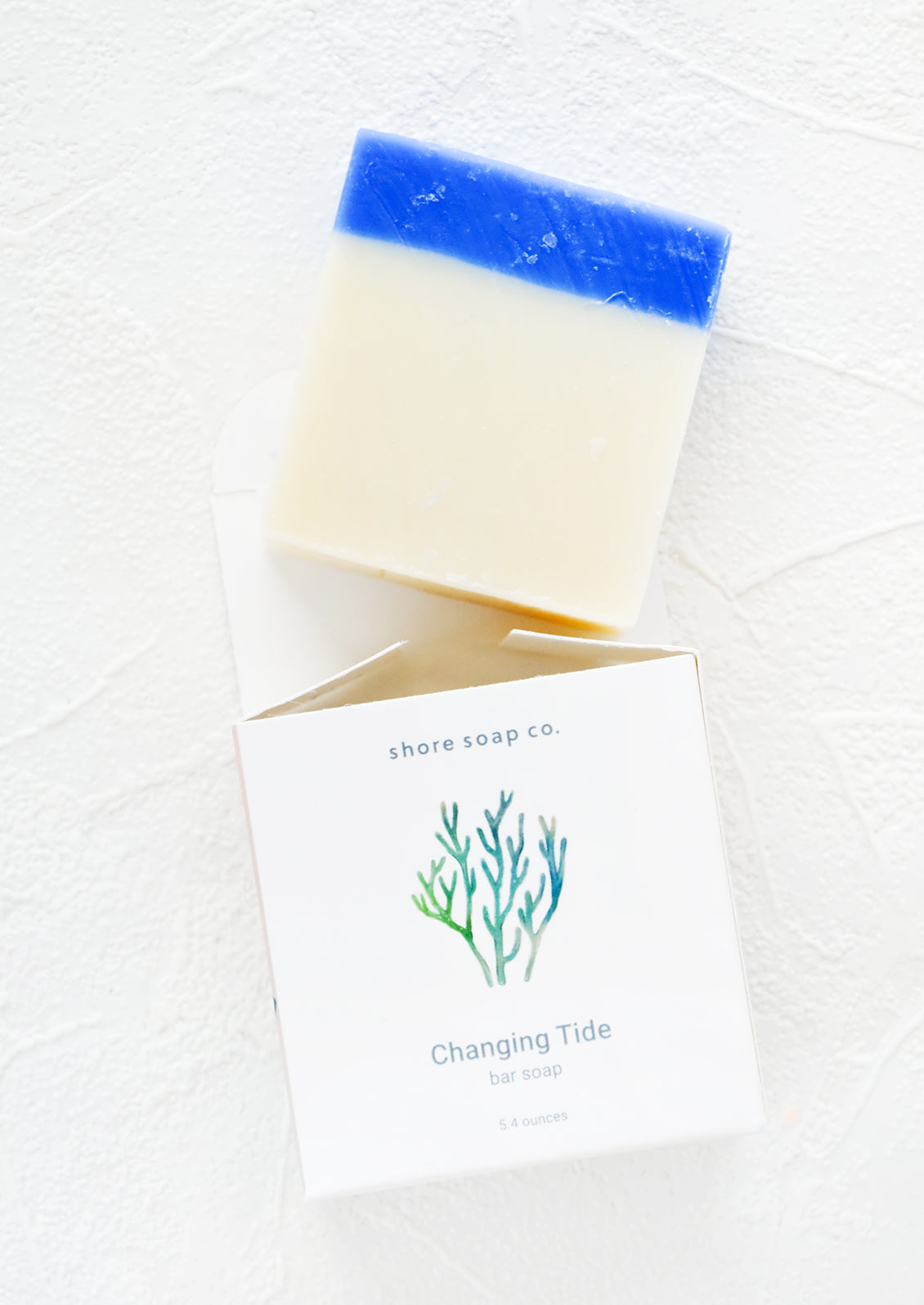 Square bar soap in blue & white emerging from nautical themed packaging