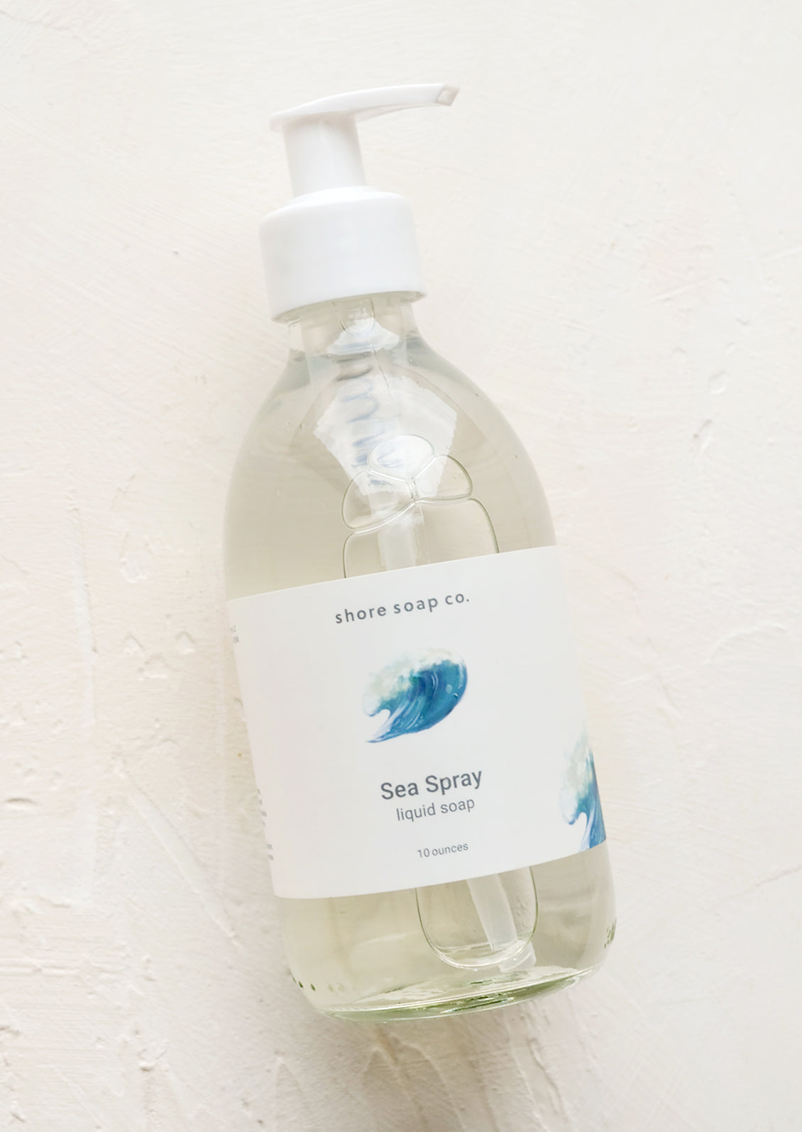 A glass pump bottle containing liquid soap in "Sea spray" scent.