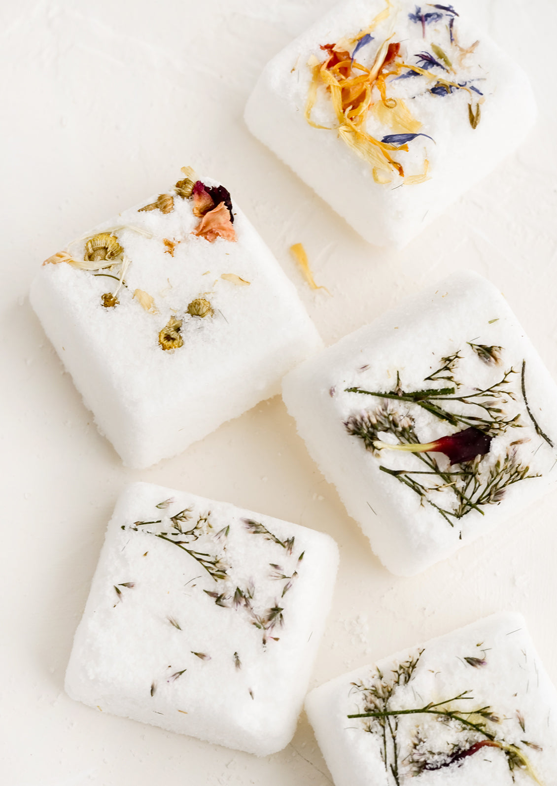 Square shower steamer tablets with embedded petals and leaves.
