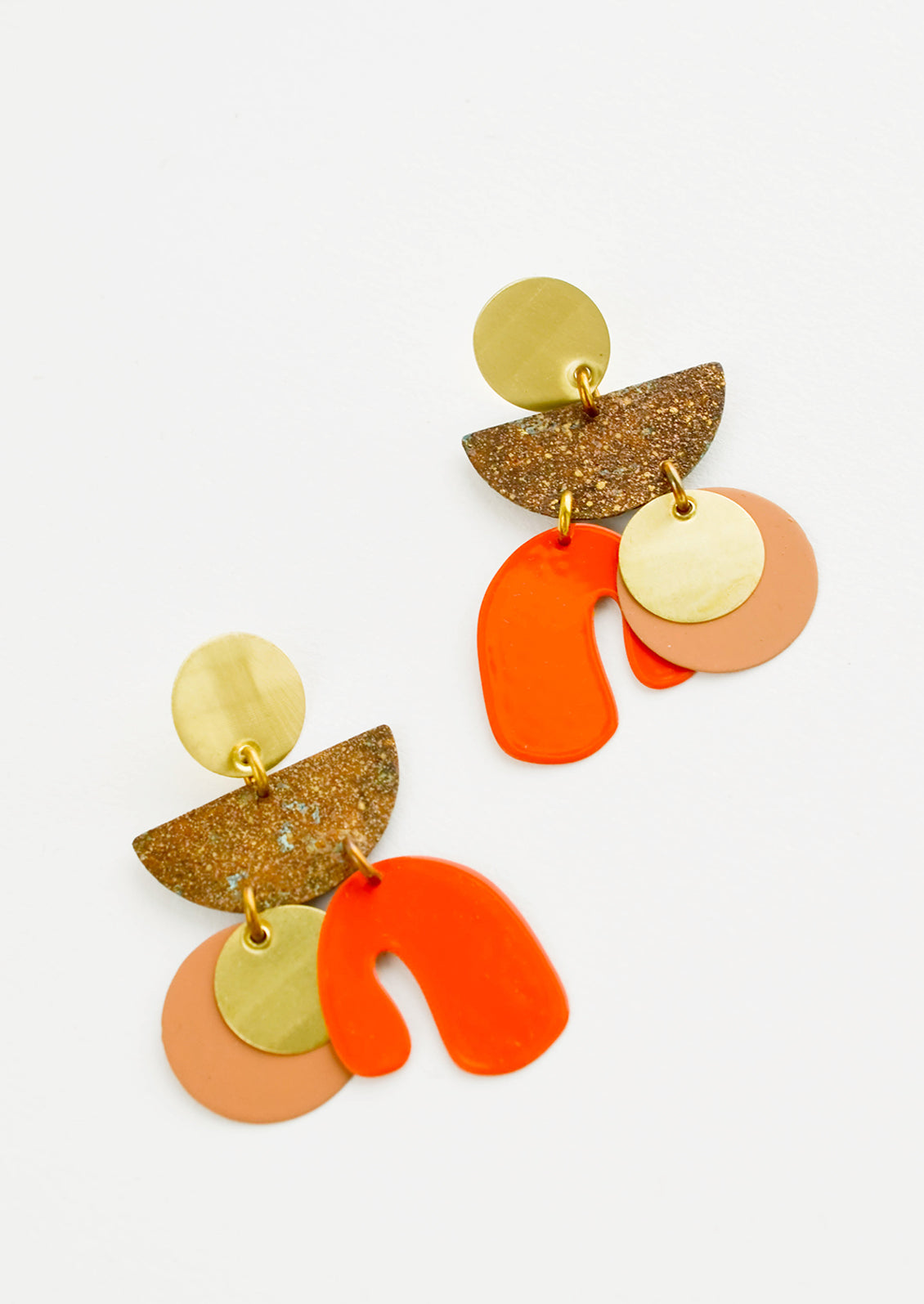 Earrings with layered circles and abstract shapes of gold, nude, bright orange and patina brass.