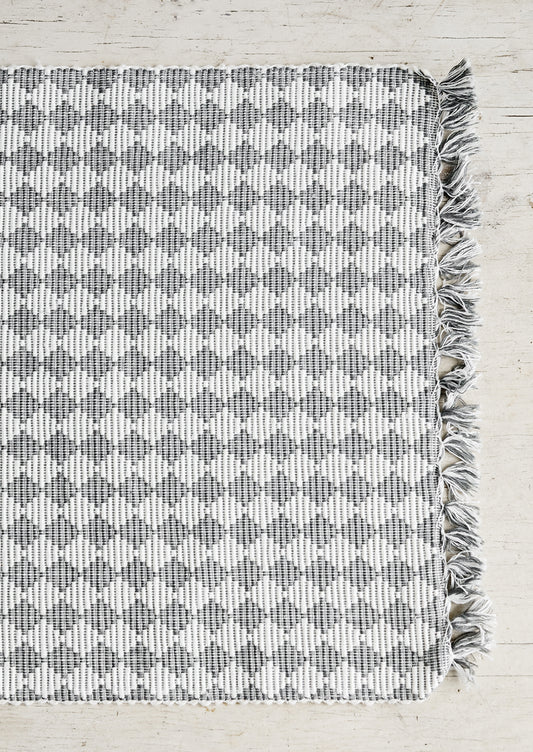 A grey and white placemat with triangular checkered pattern.
