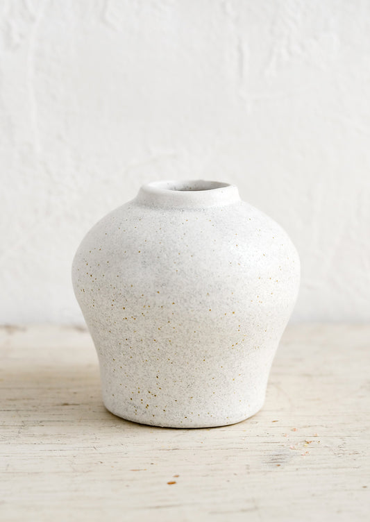 A small white ceramic vase in an urn-like shape.