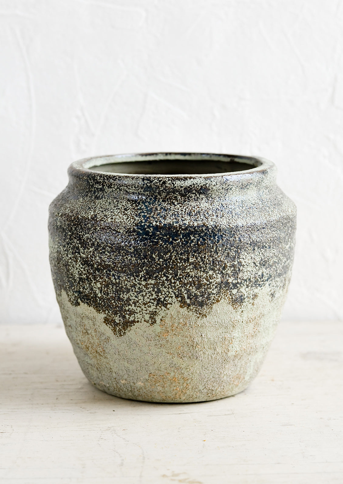 A ceramic planter in a distressed mossy green patina.