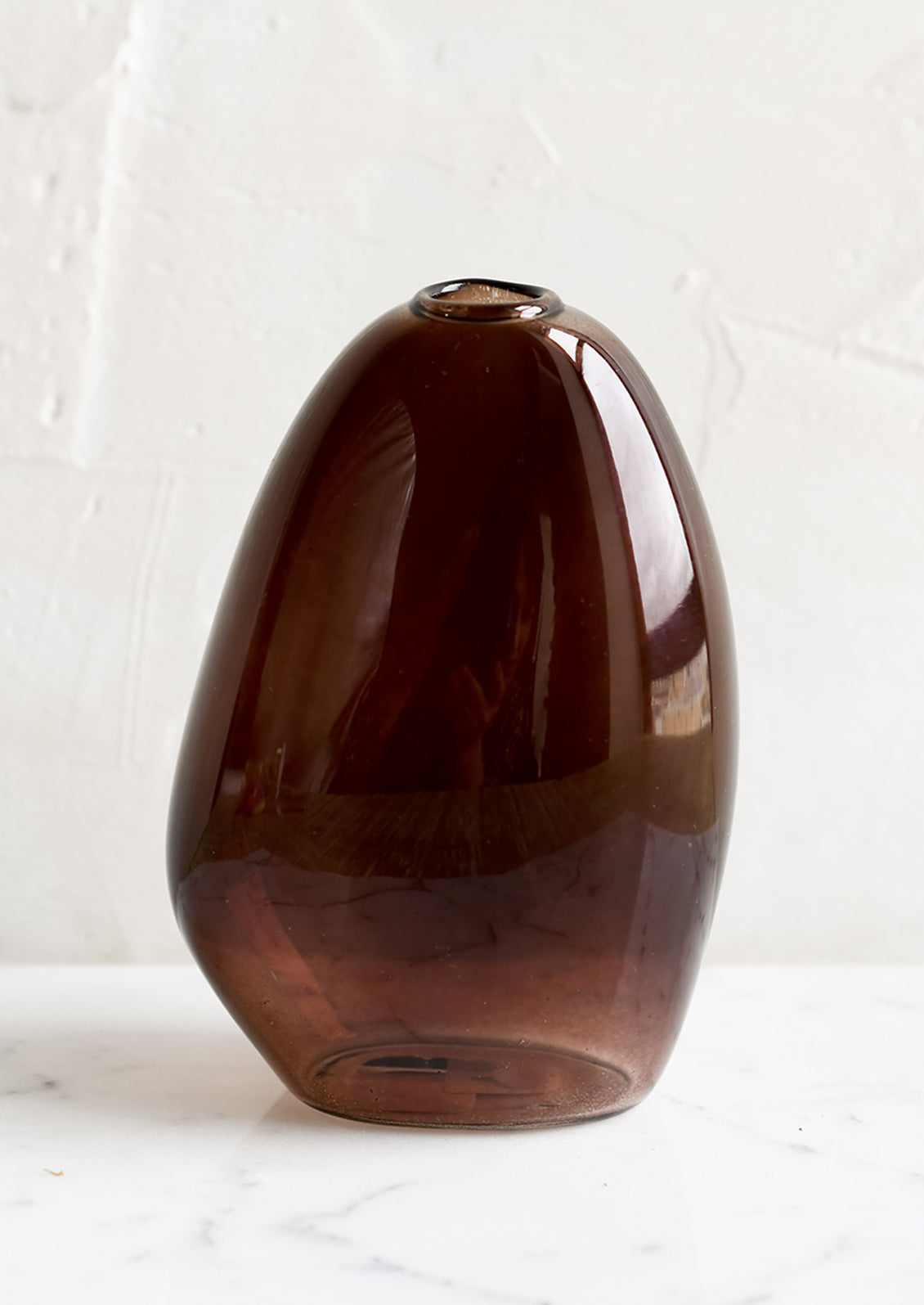 An asymmetrical bud vase in brown colored glass.