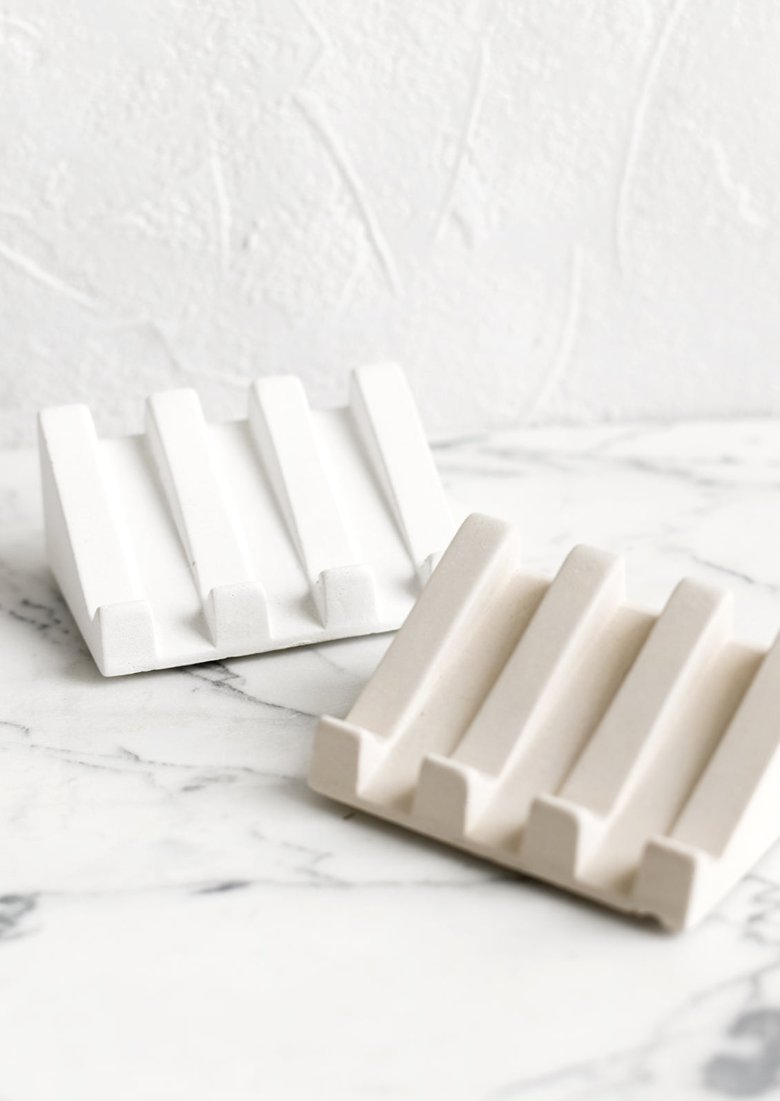 Slanted soap dishes made from white and beige concrete.