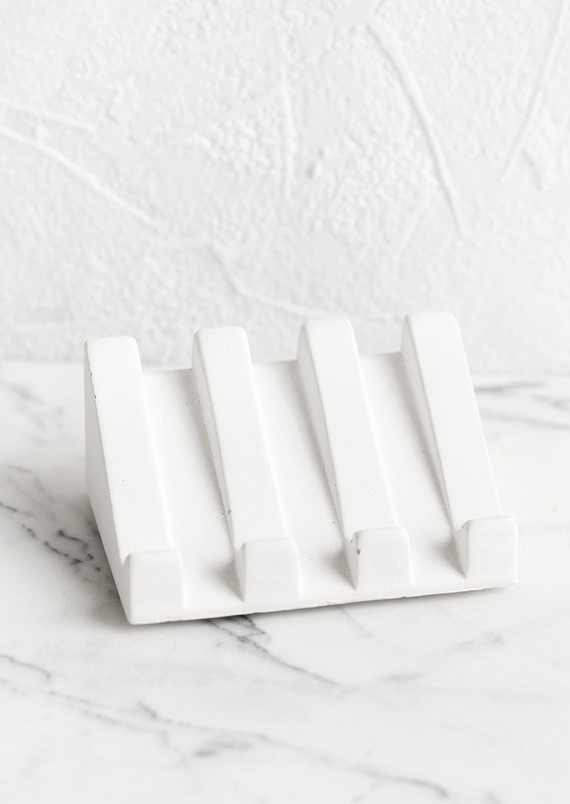 A slanted soap dish made in white concrete.
