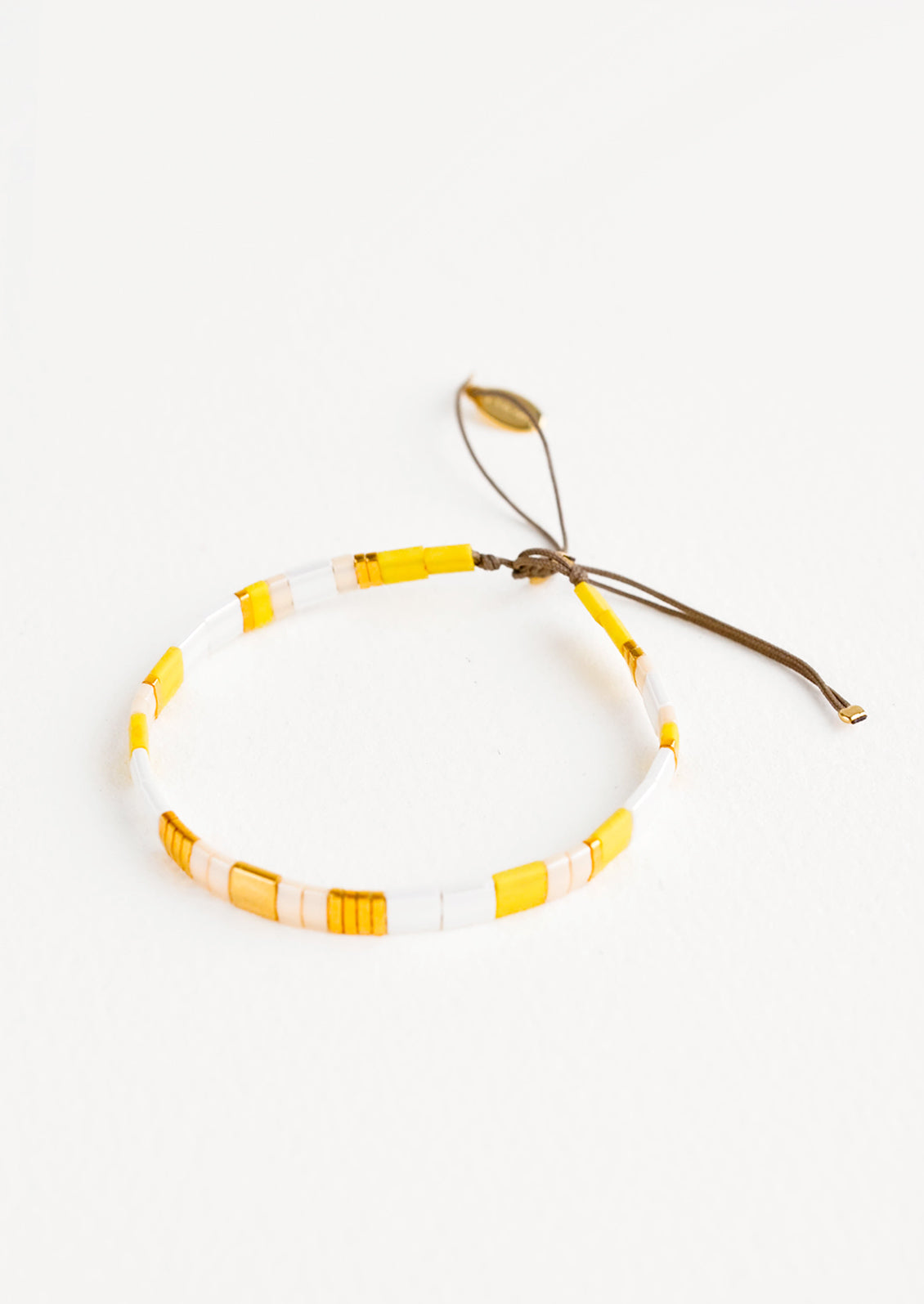 Bracelet featuring flat yellow and white glass beads interspersed with flat gold bead on an adjustable cord.