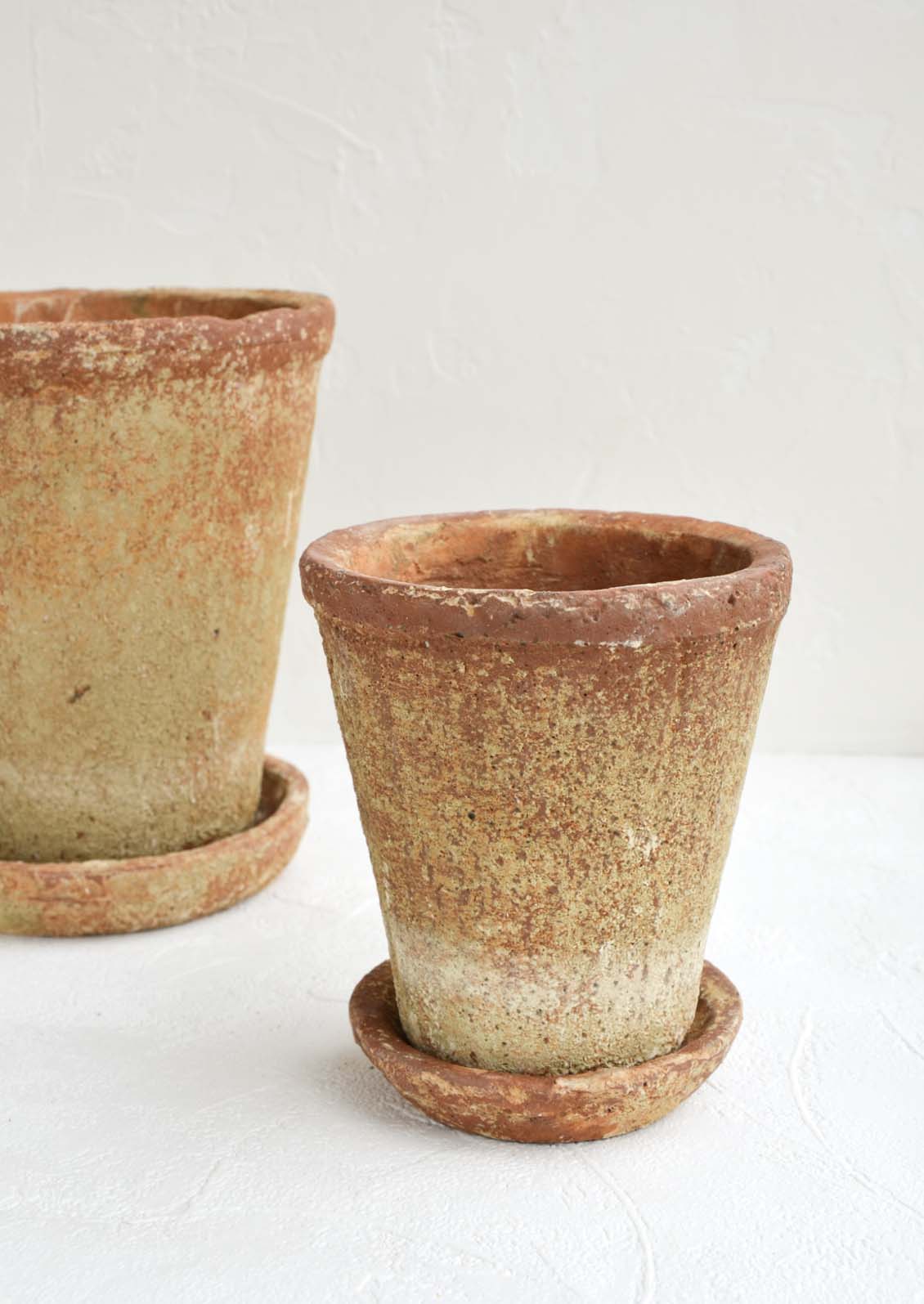 Two rustic, heavily textured terracotta clay planters in a small and medium size with saucer.