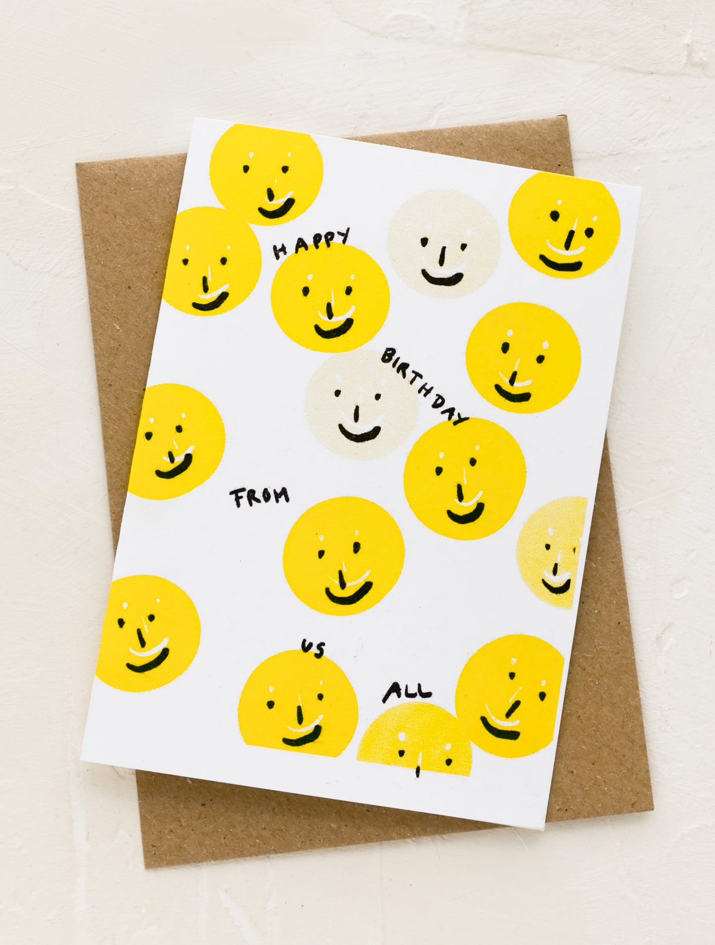A greeting card with smiley faces reading "happy birthday from us all".