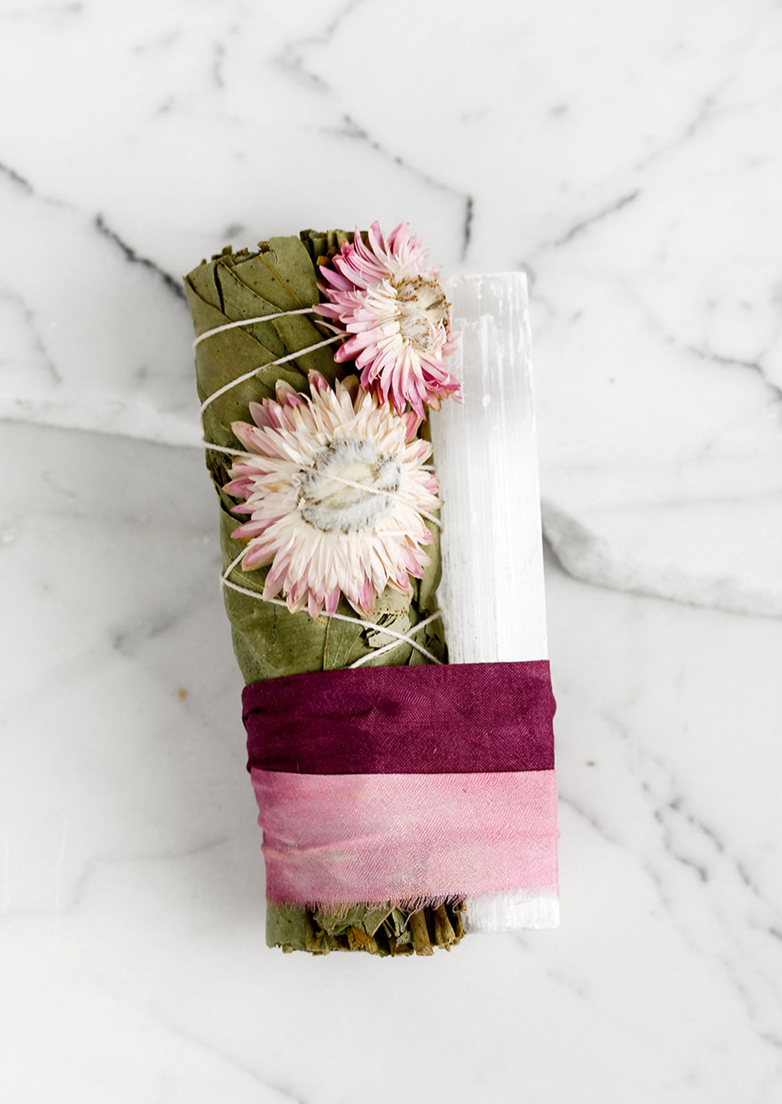 A eucalyptus and selenite smudge bundle bound with pink ribbon.