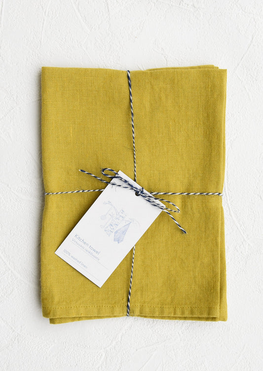 A folded chartreuse linen tea towel tied in baker's twine with a decorative hangtag