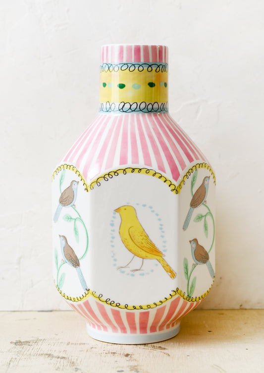 A graphic print vase with pink stripes and three-dimensional shape with bird motif.