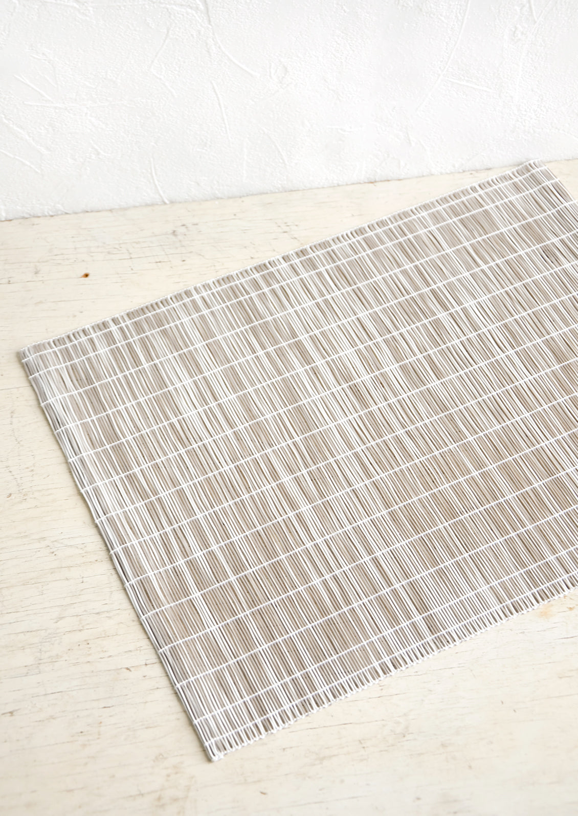 A placemat made from intertwined, vertically woven vinyl in black and white.