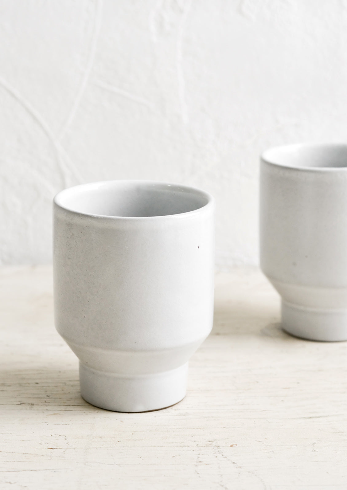 Glossy white ceramic cups with geo tapered bottom.