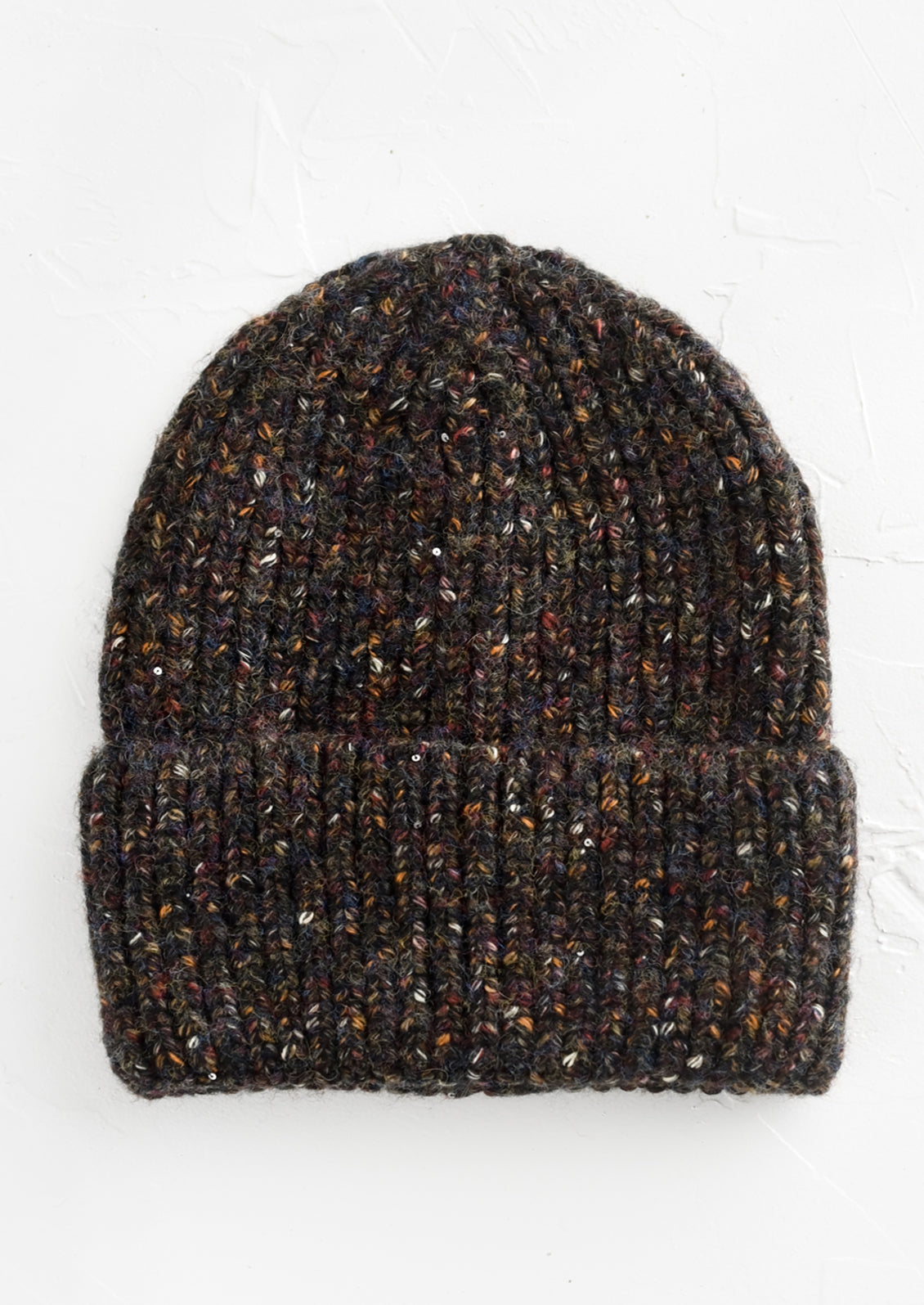 A knit beanie hat with cuffed rim made in black yarn with earth tone speckles.