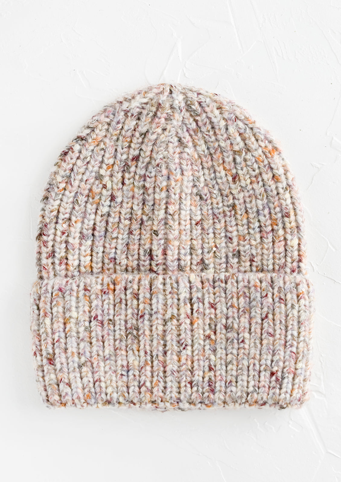 A knit beanie hat with cuffed rim made in multicolor speckled ivory yarn.