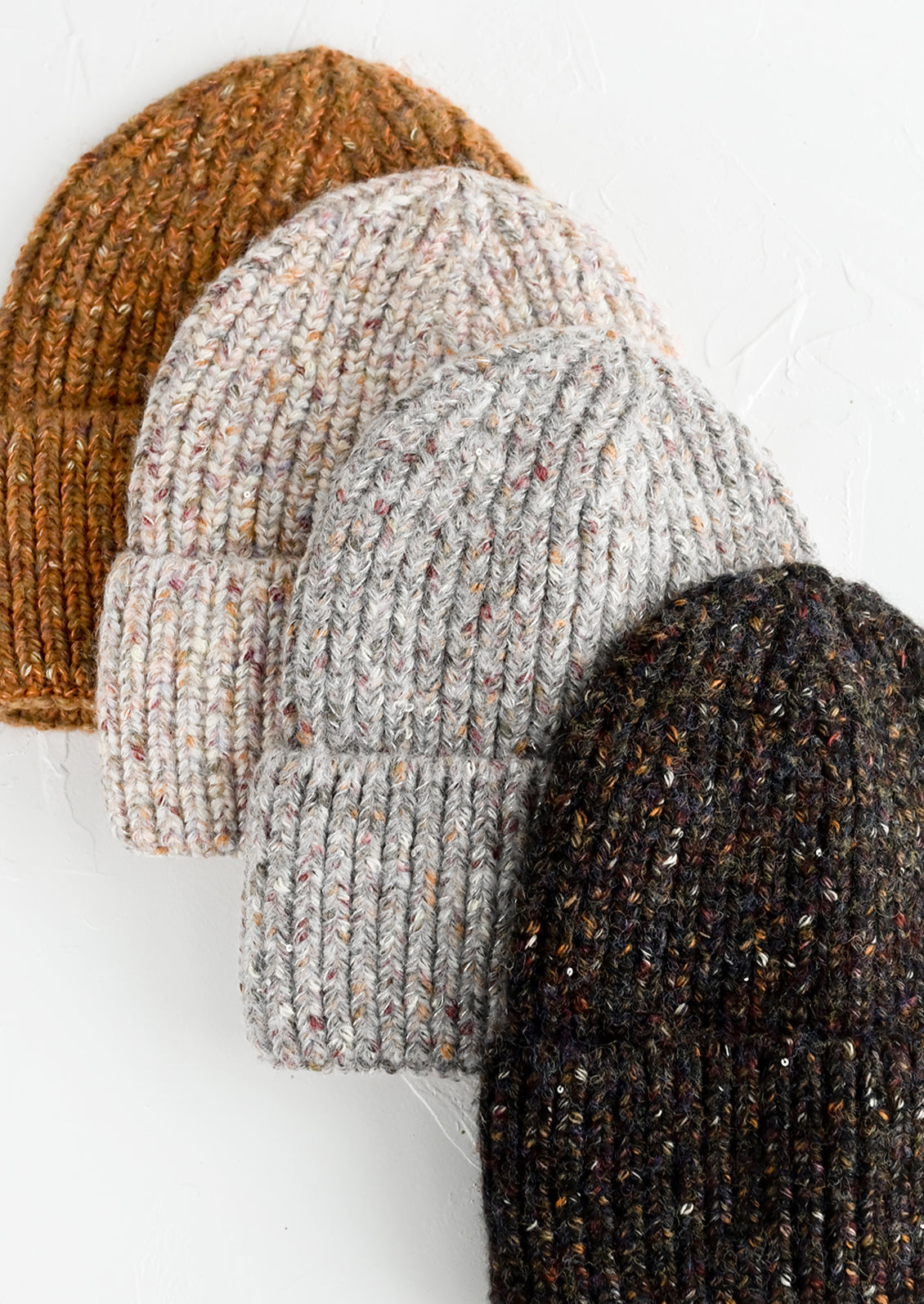 Four speckled yarn beanies in assorted colors.
