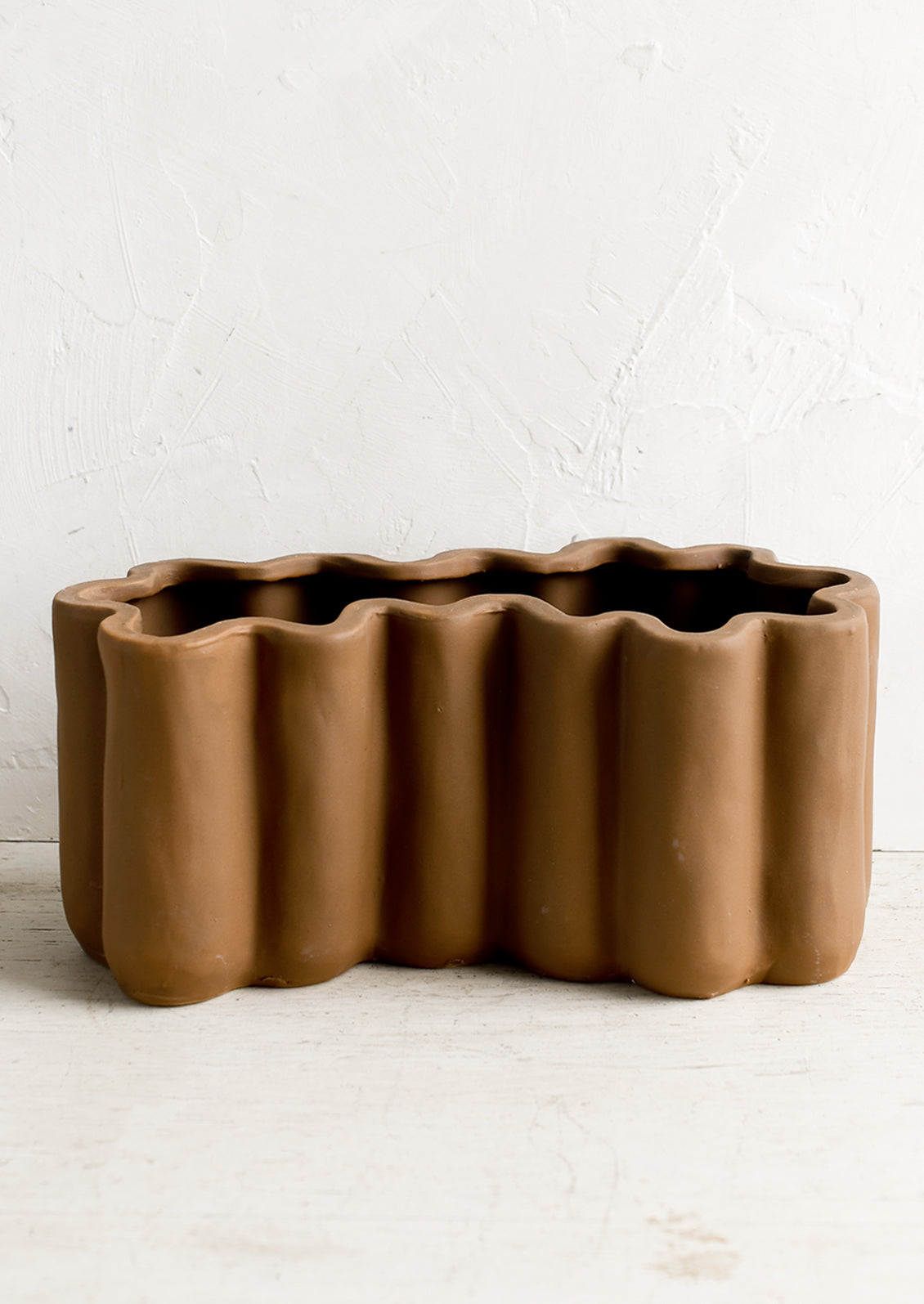 A brown ceramic planter in squiggle shape.