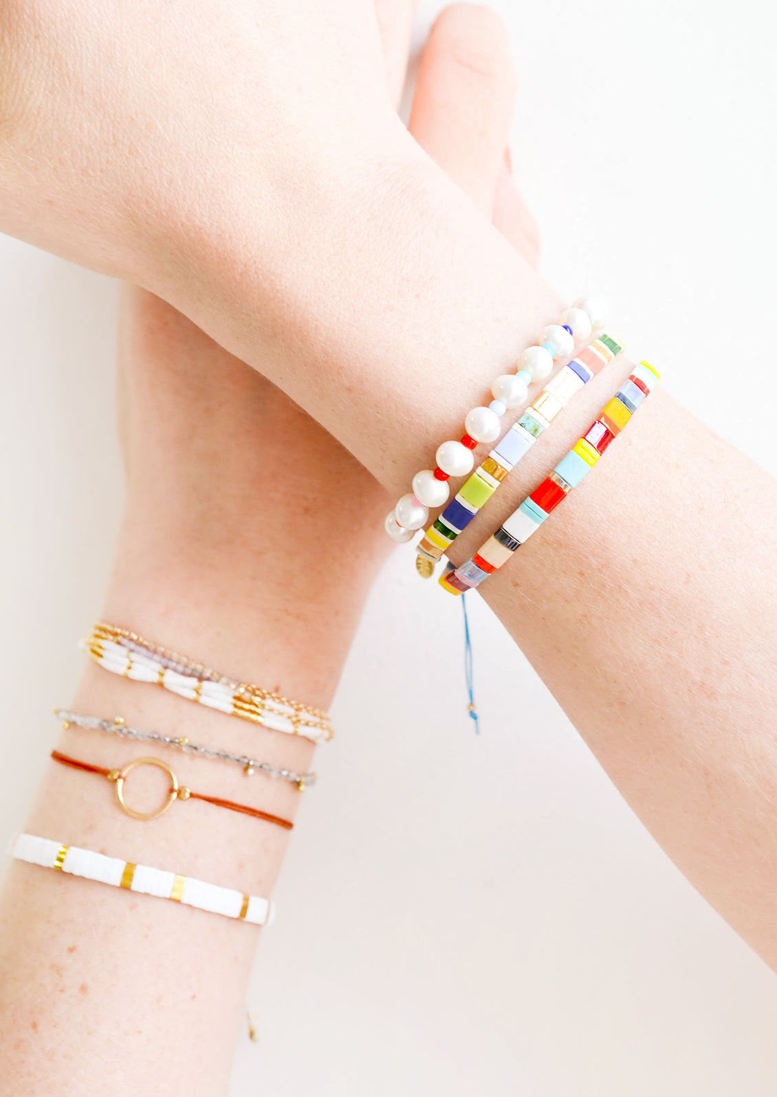 Model shot showing wrists wearing multiple styles of bracelets.