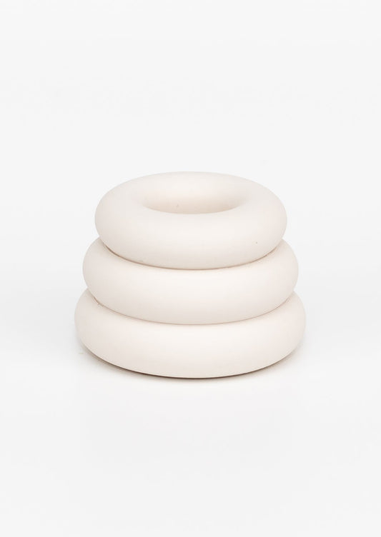 A taper candle holder with 3-layer stacked donut shape in white.