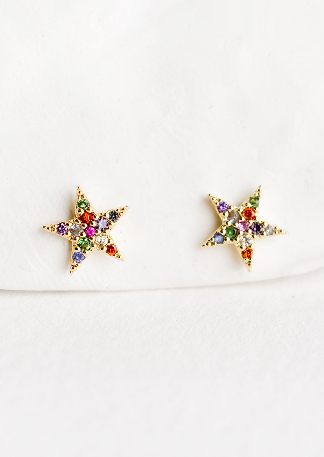 A pair of star shaped gold stud earrings with multicolor crystal pave.